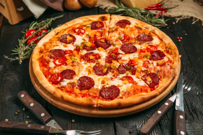 delicious-savory-pizza-with-pepperoni-and-pepper-on-the-black-board-on-the-dark-wooden-background
